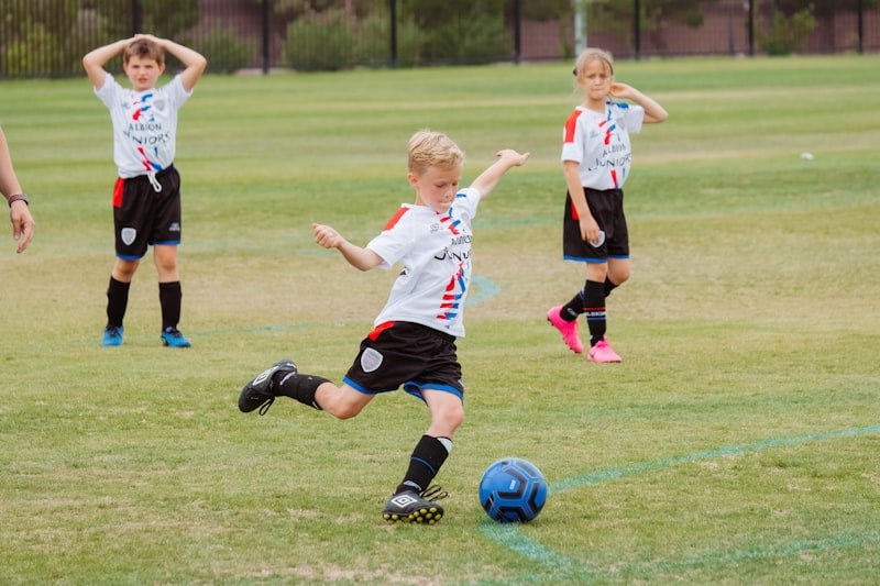 Kind kickt einen Ball auf dem Rasen
